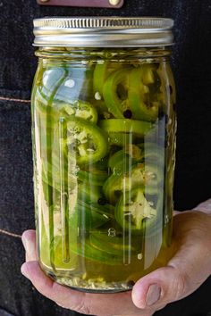 a person holding a jar filled with pickles