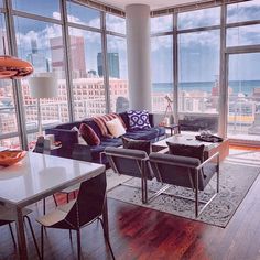 a living room filled with furniture and large windows overlooking the cityscape in the distance