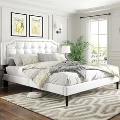 a white bed sitting in a bedroom on top of a hard wood floor next to a window