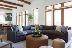 a living room filled with lots of furniture next to large windows and wooden beams on the ceiling