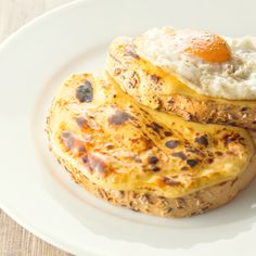 two baked potatoes on a white plate topped with an egg