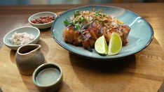 a plate with meat, rice and limes on it sitting on a wooden table