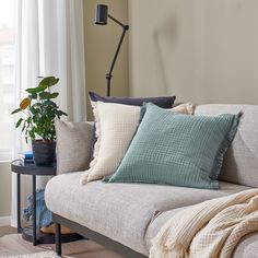 a couch with several pillows on it and a lamp in the corner next to it