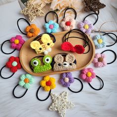 several crocheted animal headbands are arranged on a wooden tray with flowers