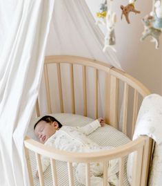 a baby sleeping in a crib next to stuffed animals