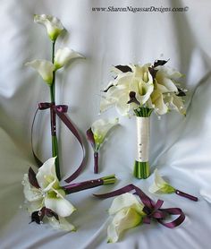 two vases with flowers and ribbons on a bed