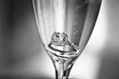 a close up of a wine glass with a diamond ring on it