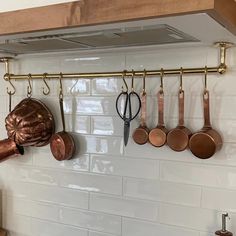 pots and pans are hanging on the kitchen wall