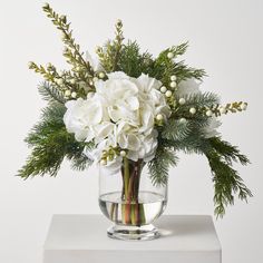 a vase filled with white flowers and greenery