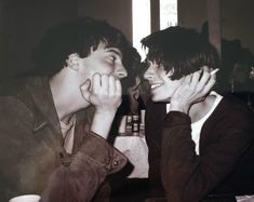 two young men sitting next to each other at a table