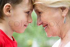 an older woman and young boy are looking at each other's faces, smiling