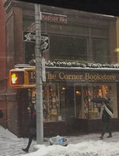 people walking in the snow near a corner bookstore