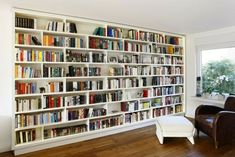 a large book shelf filled with lots of books in a living room next to a window