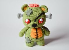 a crocheted green teddy bear with red eyes and horns on it's head