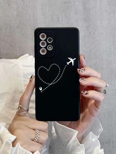 a woman holding up her phone case with an airplane and heart on it