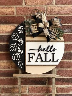 a black and white sign that says hello fall hanging on the side of a brick wall