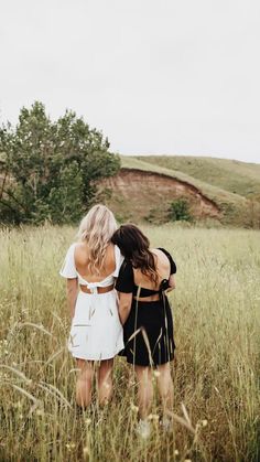 two women standing in tall grass with their backs to each other