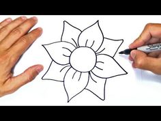 two hands are drawing a flower on a piece of paper