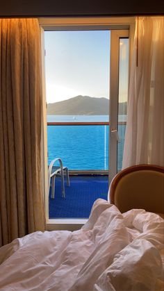 a bed sitting next to a window with a view of the ocean and mountains in the distance