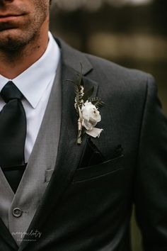 a man wearing a suit and tie with a flower in his lapel