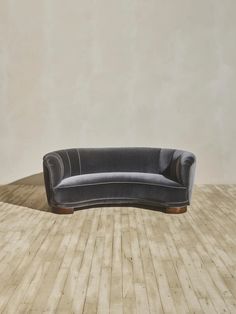 a grey couch sitting on top of a wooden floor next to a white wall in an empty room