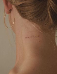 a woman with a small tattoo on her left side behind her ear that says, love