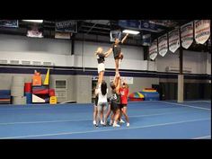 a group of young people standing on top of each other in a gym holding onto one another