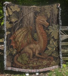 a tapestry with a dragon on it hanging from a fence in front of some trees