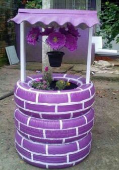 a potted plant sitting on top of a purple tire covered stand with flowers in it