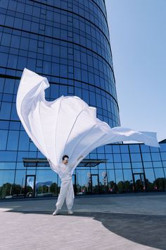 a person standing in front of a tall building with a large white cloth covering their body