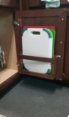 a kitchen cabinet with several cutting boards in it