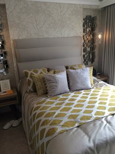 a bed with yellow and white pillows in a bedroom