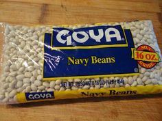 a bag of goya navy beans sitting on top of a wooden table next to a knife