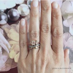 a woman's hand with two wedding rings on her left and the other hand holding an engagement ring