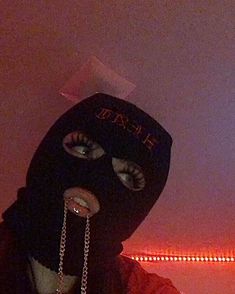 a person wearing a black mask and chain around their neck