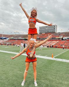 two cheerleaders are doing tricks on the field