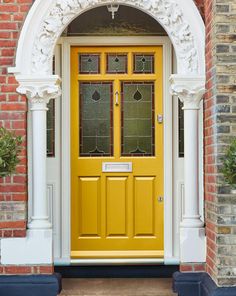 a yellow front door with arched glass and white trim on an old red brick building