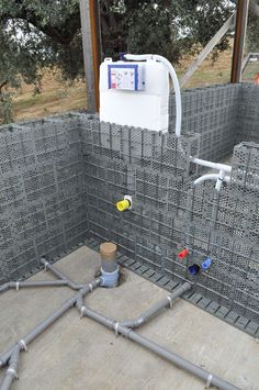 an outdoor shower in the middle of a concrete floor with pipes running from it to the ground