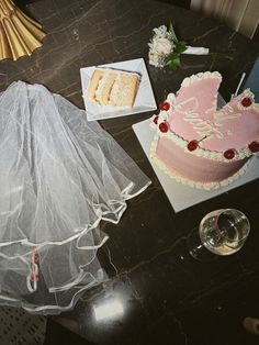 a table topped with a pink cake next to a glass of wine and a piece of cake