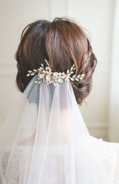 a woman wearing a veil with flowers on it's head is seen from behind