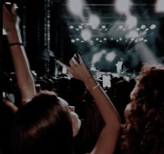 a group of people at a concert with their hands in the air and lights on