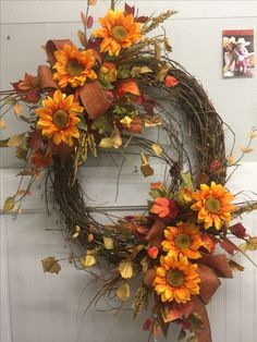 a wreath with sunflowers and fall leaves on the side of a white door