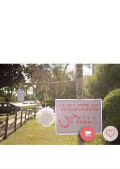 a welcome sign hanging from a wooden pole in front of a fence and grass area