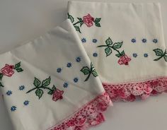 two white napkins with pink and blue flowers on them sitting next to each other