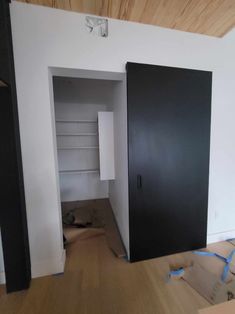 an empty room with two black doors and some boxes on the floor next to it