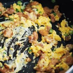 an omelet is being cooked in a pan with meat and cheese on top