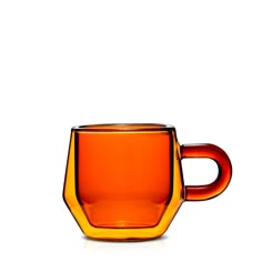 an orange glass cup sitting on top of a white table