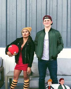 a man and woman standing next to each other in front of a couch with one holding a frisbee