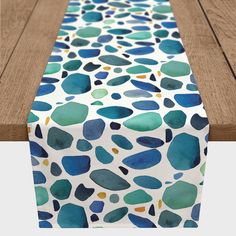 a table runner with blue, green and yellow pebbles printed on the side by wood planks