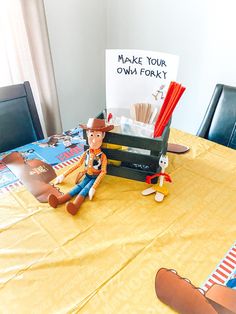 a toy cowboy sitting on top of a table next to a sign that says make your own forky